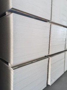 Large stacks of white drywall sheets neatly arranged in a warehouse setting.