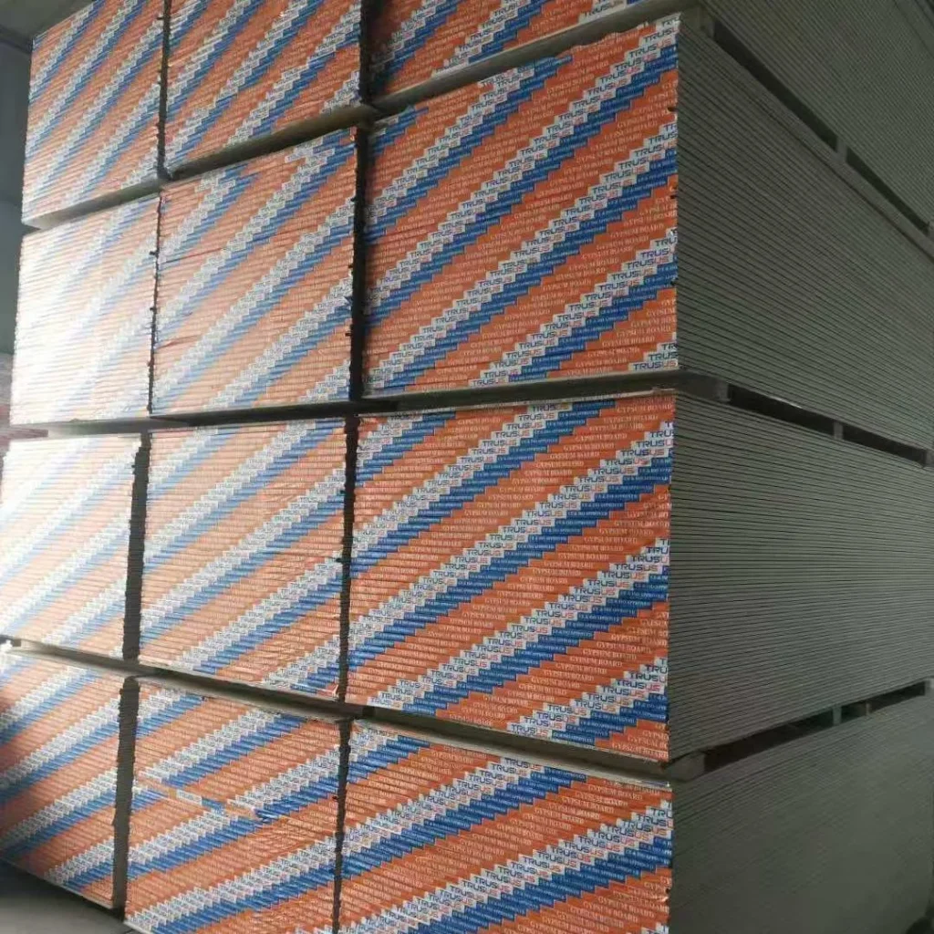 Multiple stacks of drywall sheets with colorful edging in a warehouse setting, displaying strong geometric lines.