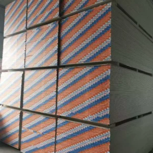 Multiple stacks of drywall sheets with colorful edging in a warehouse setting, displaying strong geometric lines.